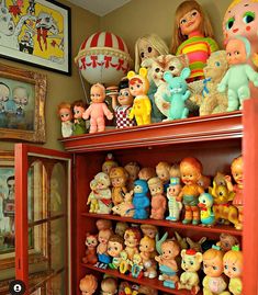 a red book shelf filled with lots of little toy figurines on top of it