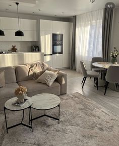 a living room filled with furniture next to a dining room table and chairs on top of a rug