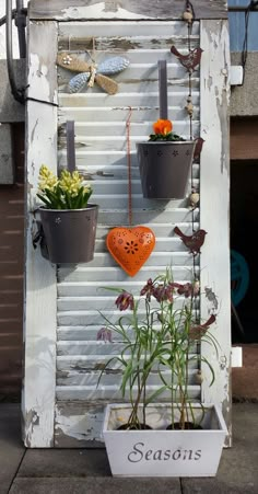 an old shuttered door is decorated with pots and plants as well as a sign that says season's greetings