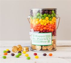 a bucket filled with lots of candy sitting on top of a white table next to other candies