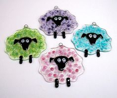 four glass sheep ornament hangings on a white table with black eyes and pink, green, blue, and purple beads