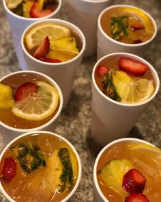 several cups filled with different types of fruit and drinks on top of a marble table