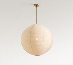 a white paper ball hanging from a gold colored ceiling fixture in an empty room with no one around it