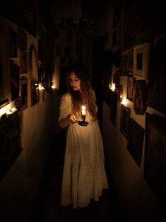 a woman standing in the dark holding candles