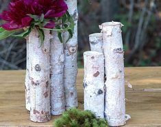 three tall vases with flowers in them sitting on a table