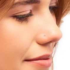 a close up of a woman's nose and nose piercing on her left side