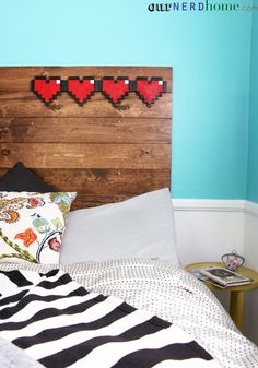 a bed with two pillows on top of it next to a wooden headboard that has hearts painted on it