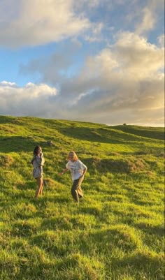 two children are running in the grass on a hill