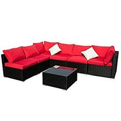 an outdoor furniture set with red cushions and white pillows on the back, including a coffee table