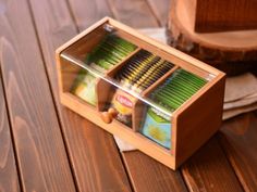 a wooden box filled with different colored pencils on top of a wooden table next to a piece of wood