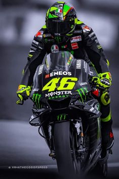 a man riding on the back of a motorcycle down a race track in green and black