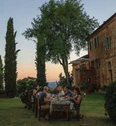 a group of people sitting at a table outside in the sun set up for dinner