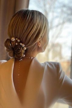 a woman with her back to the camera, wearing a white dress and pearls in her hair