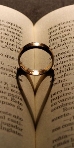 a heart shaped ring casts a shadow on an open book