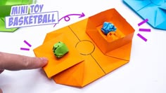 an origami box with two green and blue paper animals in it's center