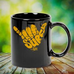 a black and yellow coffee mug sitting on top of a wooden table