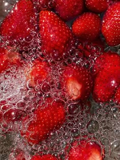 some strawberries are being washed in water and placed on top of each other with bubbles