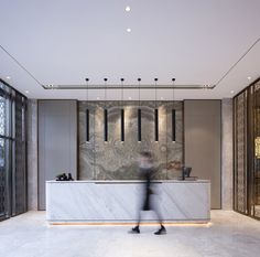 a person walking past a marble counter in a room with lots of glass doors and chandeliers