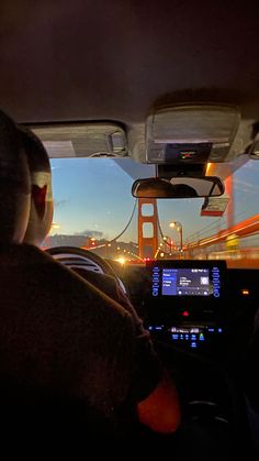 two people in a car driving over the golden gate bridge at night with lights on