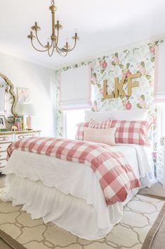 a bedroom decorated in pink and white with floral wallpaper