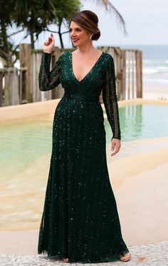 a woman standing in front of a swimming pool wearing a green dress with sequins on it