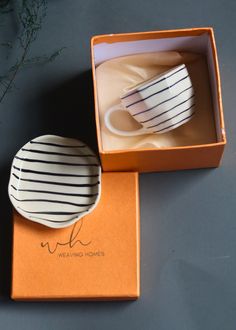 two white cups in a box sitting on top of a table