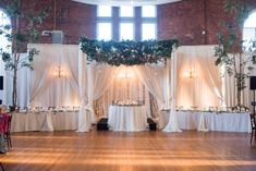 a banquet hall decorated with white drapes and greenery