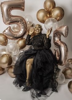 a woman is sitting in front of balloons and number fives for her 50th birthday