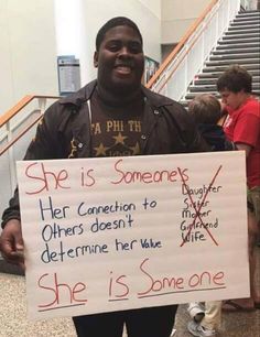 a man holding a sign that says she is someone