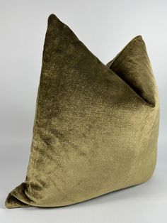 a green velvet pillow sitting on top of a white table