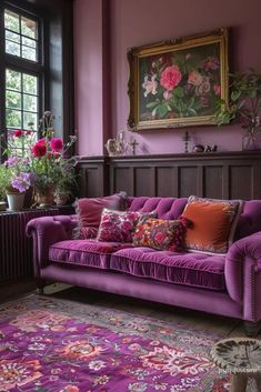 a purple couch sitting next to a window in a living room filled with furniture and flowers