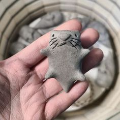 a hand holding a small gray cat shaped object