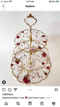 a three tiered serving tray with red flowers on the bottom and gold trimmings