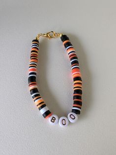 an orange, black and white beaded bracelet with the word boo spelled on it