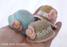 two small crocheted hats are held in the palm of someone's hand