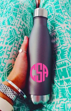 a person's hand holding a stainless steel water bottle with the initials on it