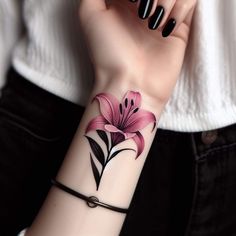 a woman's wrist with a pink flower tattoo on her left arm and black nails