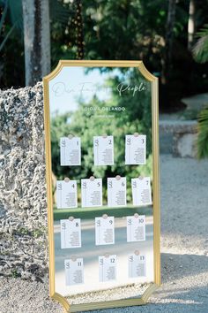 a table plan is set up on a gold framed mirror in front of a stone wall