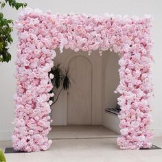 a pink flower covered archway in front of a white wall