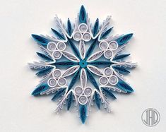 an origami snowflake made with blue and white paper on a white background