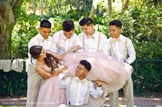 a group of men and women dressed in formal wear posing for a photo with each other