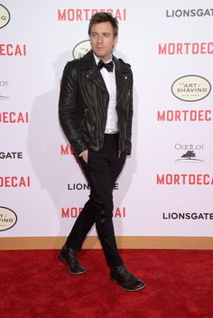 a man in a tuxedo and bow tie walks down the red carpet at an event