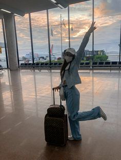 a woman with her arms in the air while holding onto a piece of luggage at an airport