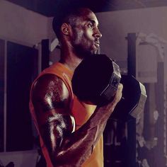 a man in an orange shirt is holding two dumbbells