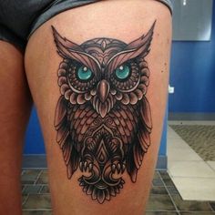 an owl tattoo on the thigh with blue eyes and green eyes is seen in this photo