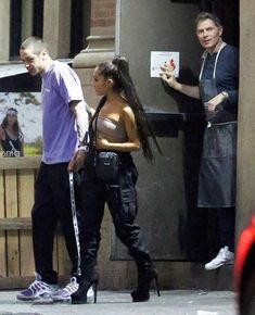 a man and woman walking down the street talking to each other while another man looks on