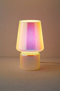 a colorful lamp sitting on top of a table next to a white wall and floor