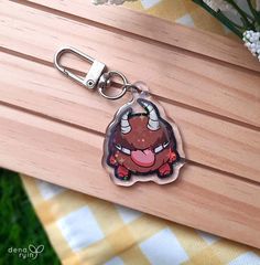 an animal shaped keychain with a cartoon character on it's face is sitting on a wooden surface