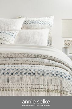 an image of a bed with white linens and blue flowers on the comforter