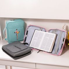 an open book and a cross are sitting on a shelf next to a bag with a bible in it